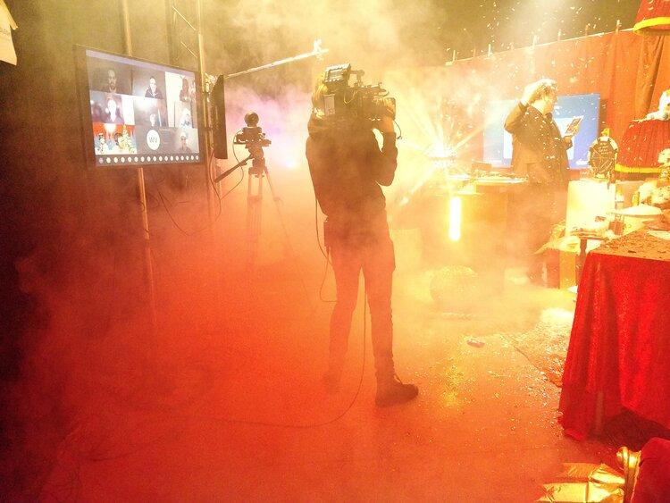 A picture of a cameraman filming a quizmaster in a livestream studio