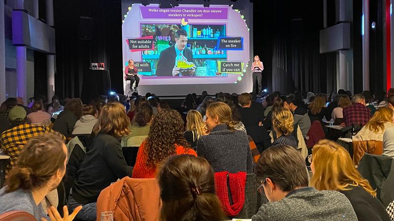 A photo of and audience watching two quizmasters presenting a quiz.